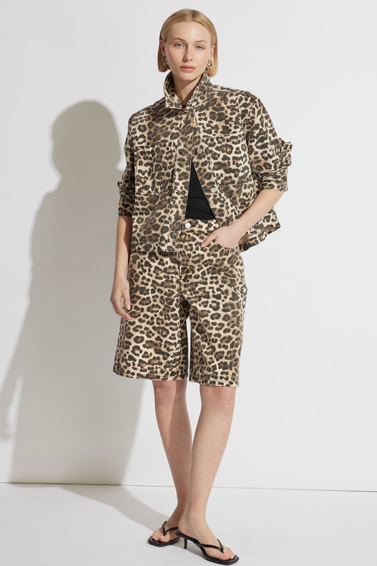 Woman wearing a relaxed leopard print denim jacket paired with matching long shorts and minimalist black sandals