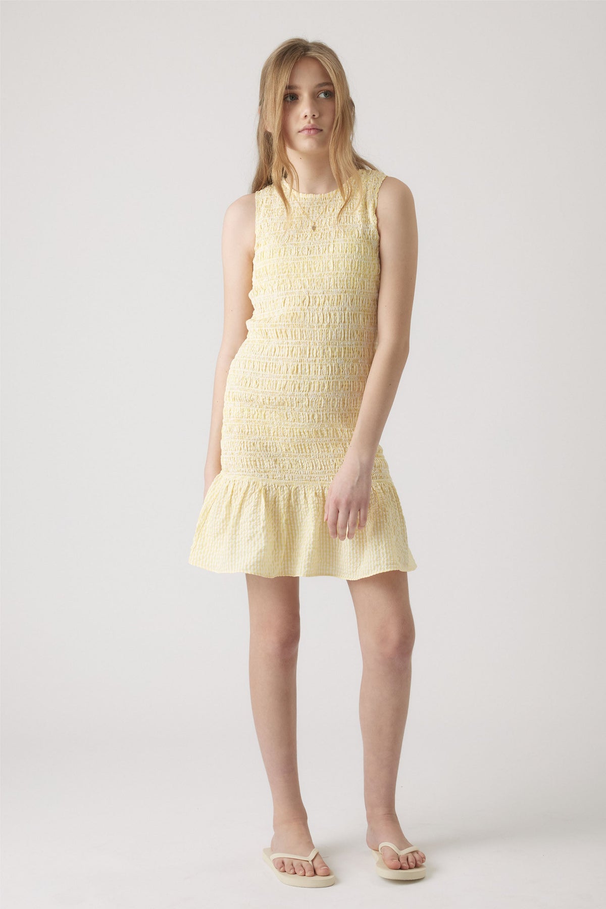 Girl wearing a yellow gingham dress with a shirred bodice and frill skirt