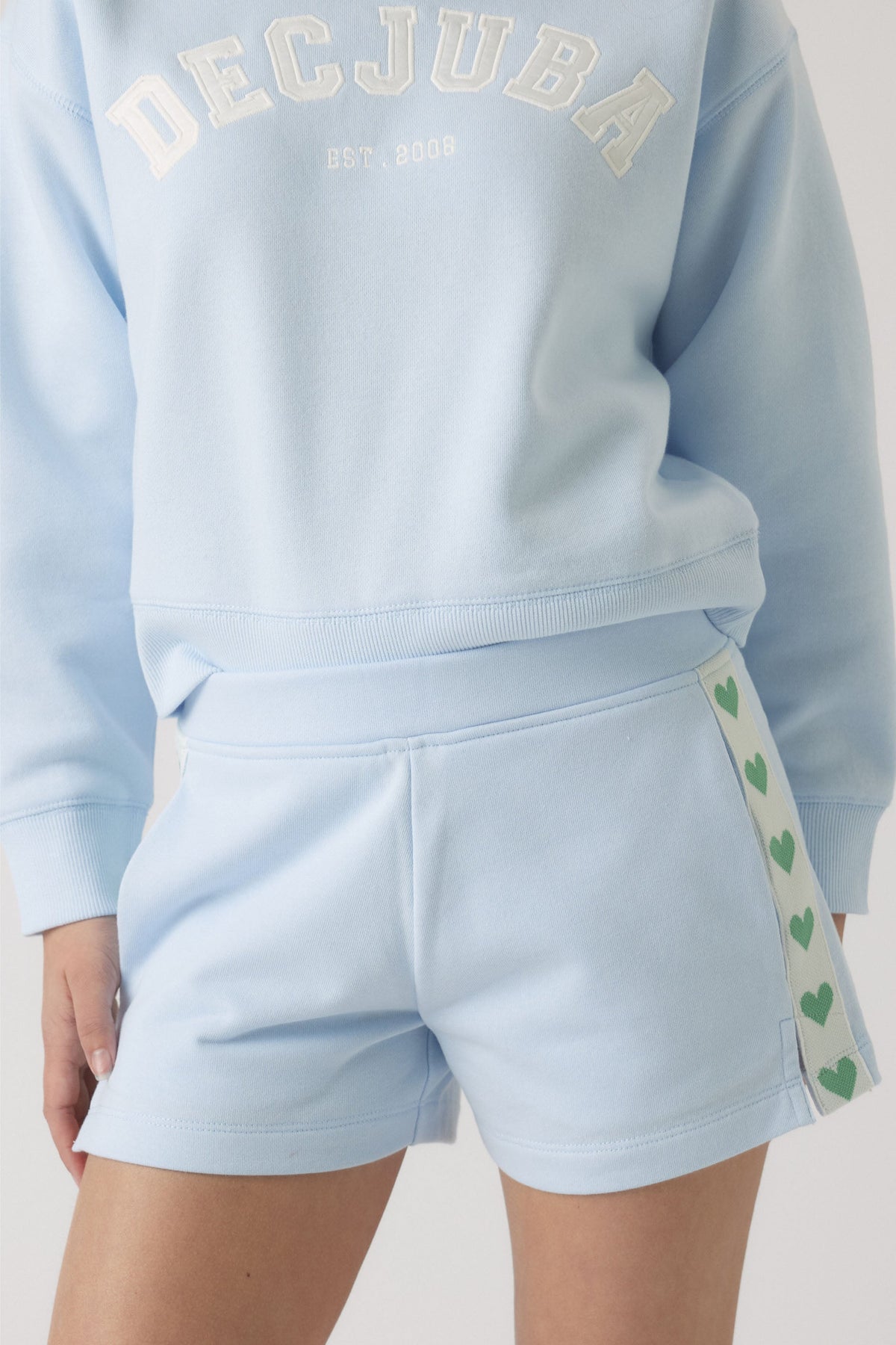 Girl wearing a light blue sweatshirt and matching shorts with heart detail on the side leg