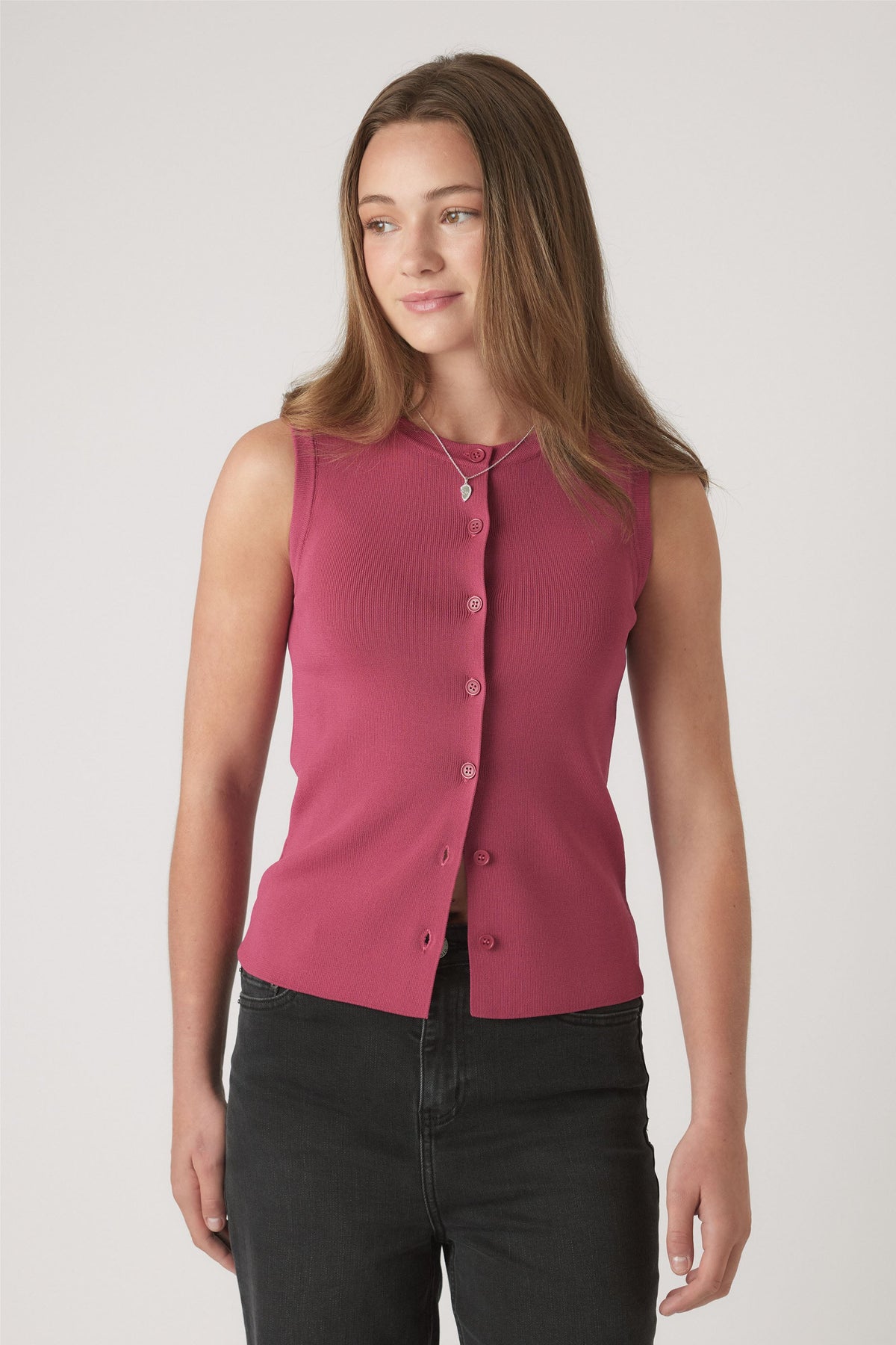 Teen girl wearing a sleeveless berry knit vest with button details, paired with black jeans and layered necklaces