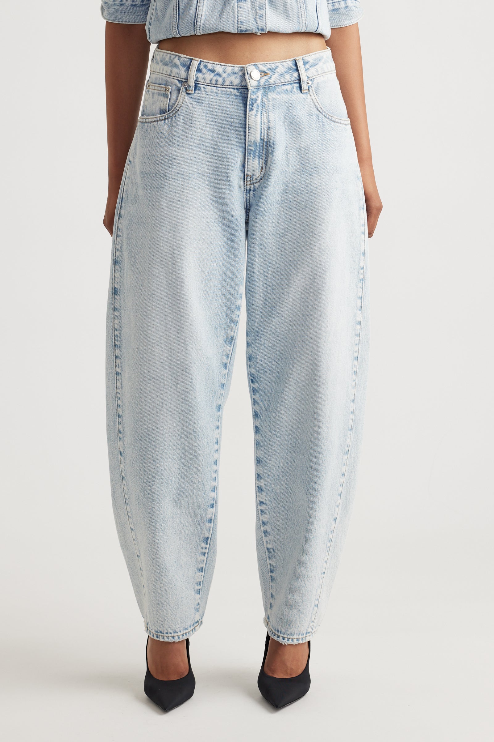 Light blue barrel leg jeans worn by a person on a white background