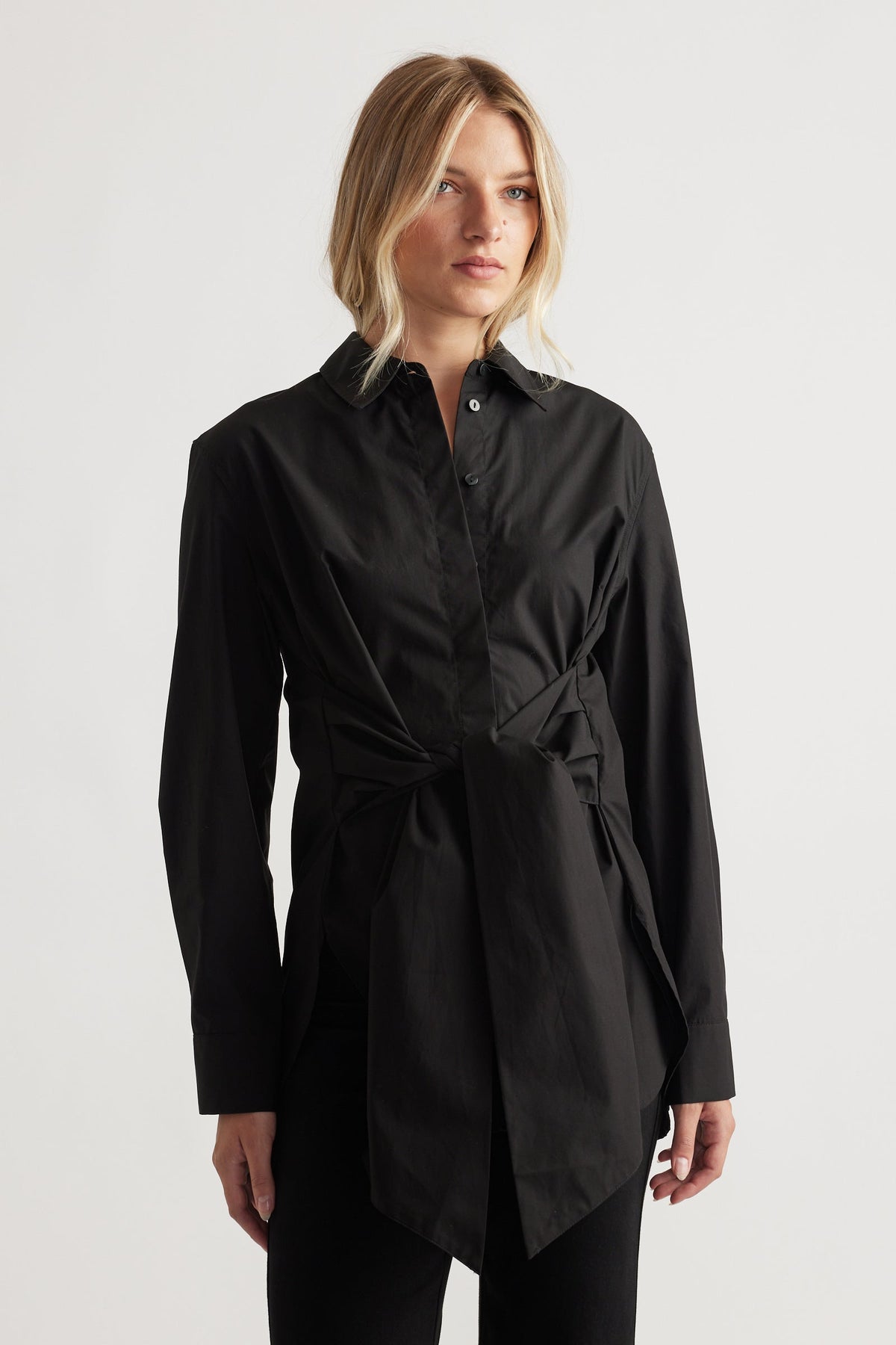 Woman wearing a black tie-front shirt with a structured collar and long sleeves for polished everyday style