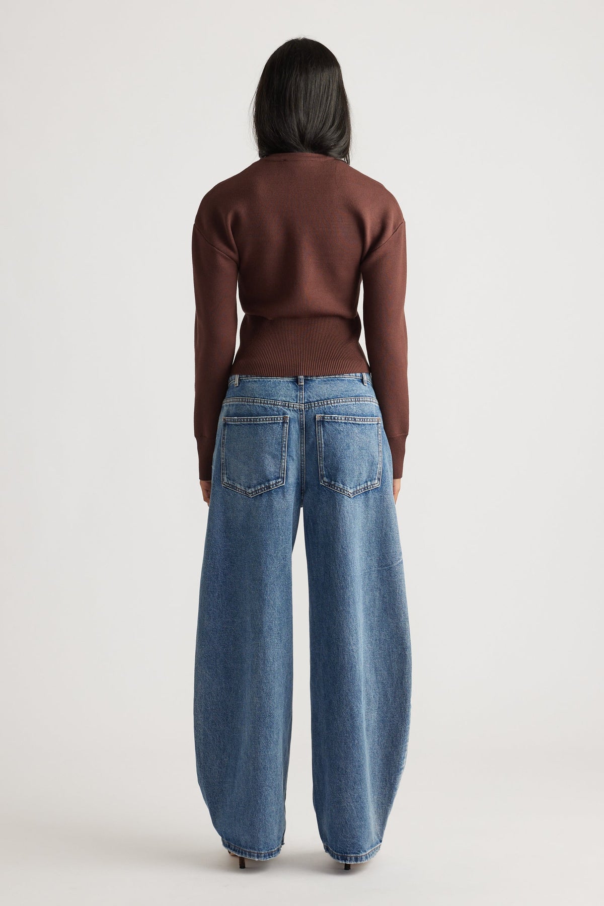 Woman wearing a rich mocha fitted knit cardigan paired with wide-leg mid-blue denim jeans for a casual look