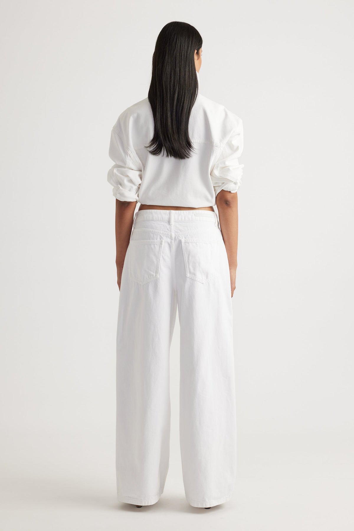 Back view of woman wearing white Elena Wide Leg Jean with high waist and relaxed fit by Decjuba Australian brand