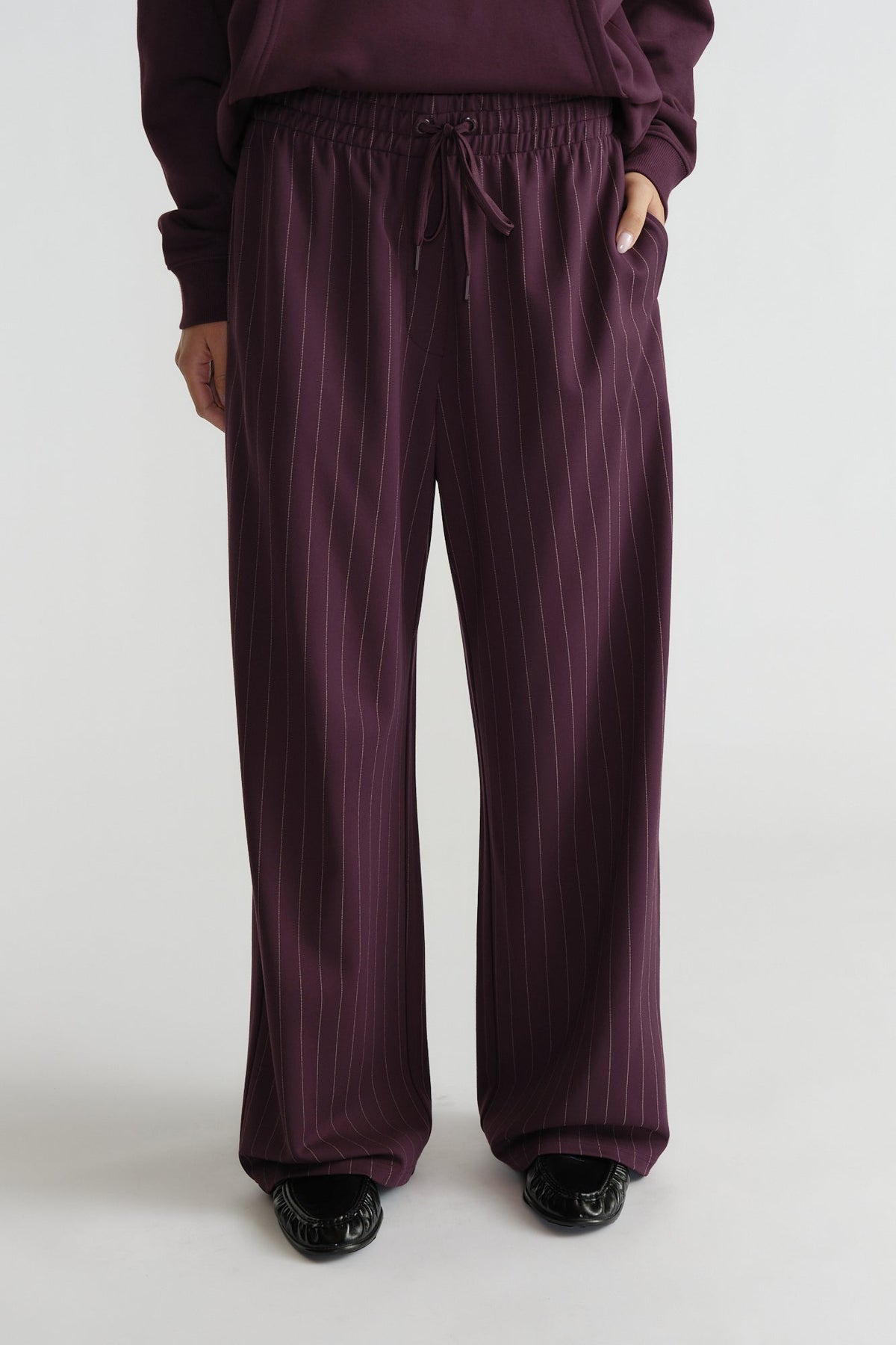 Relaxed fit pinstripe pants in deep cherry hue with elastic waist and drawstring for effortless everyday comfort.