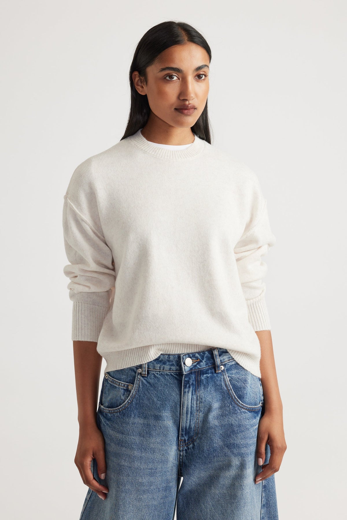 Woman wearing Crew Neck Knit Jumper in soft cream knitwear with relaxed fit, styled with casual blue denim jeans by Decjuba Australian brand