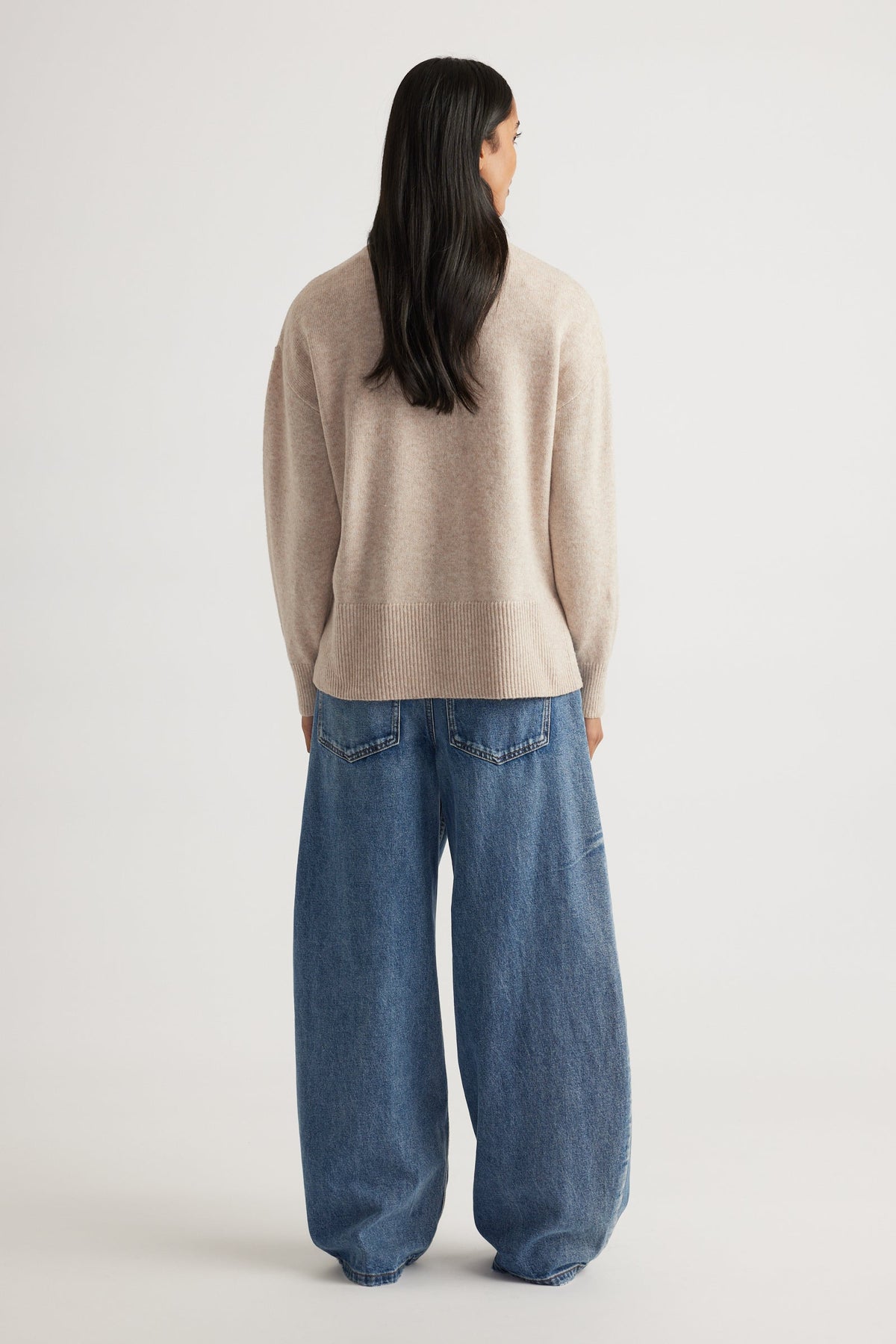 Back view of Roll Neck Knit Jumper in soft beige knitwear styled with relaxed wide-leg denim jeans by Decjuba Australian brand