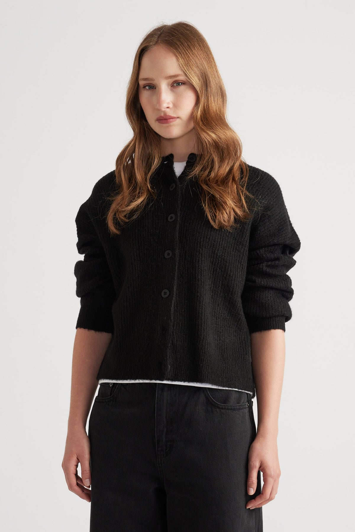 Woman wearing a cozy black knit cardigan with a relaxed fit, styled with black high-waisted pants for a casual look