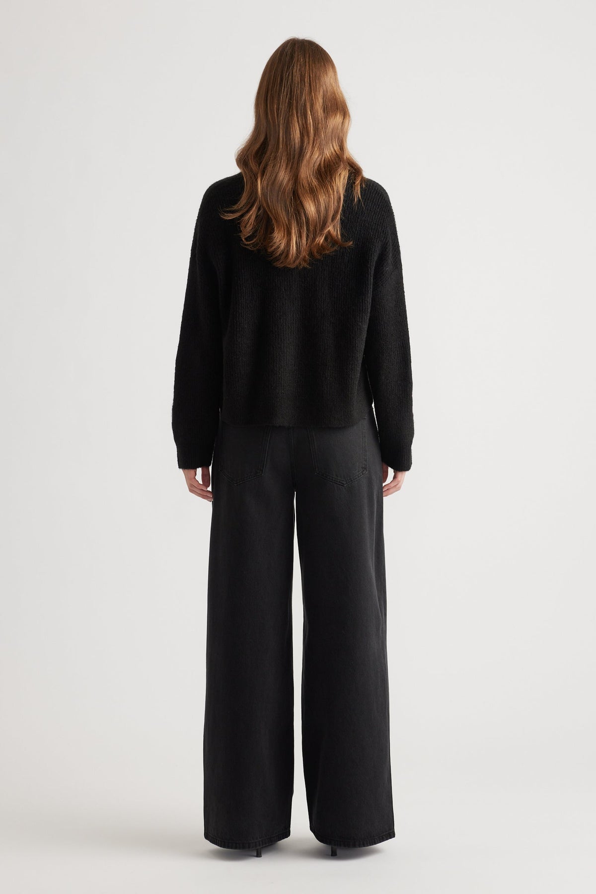 Woman wearing a cozy black knit cardigan paired with relaxed wide-leg black pants for a minimalist look