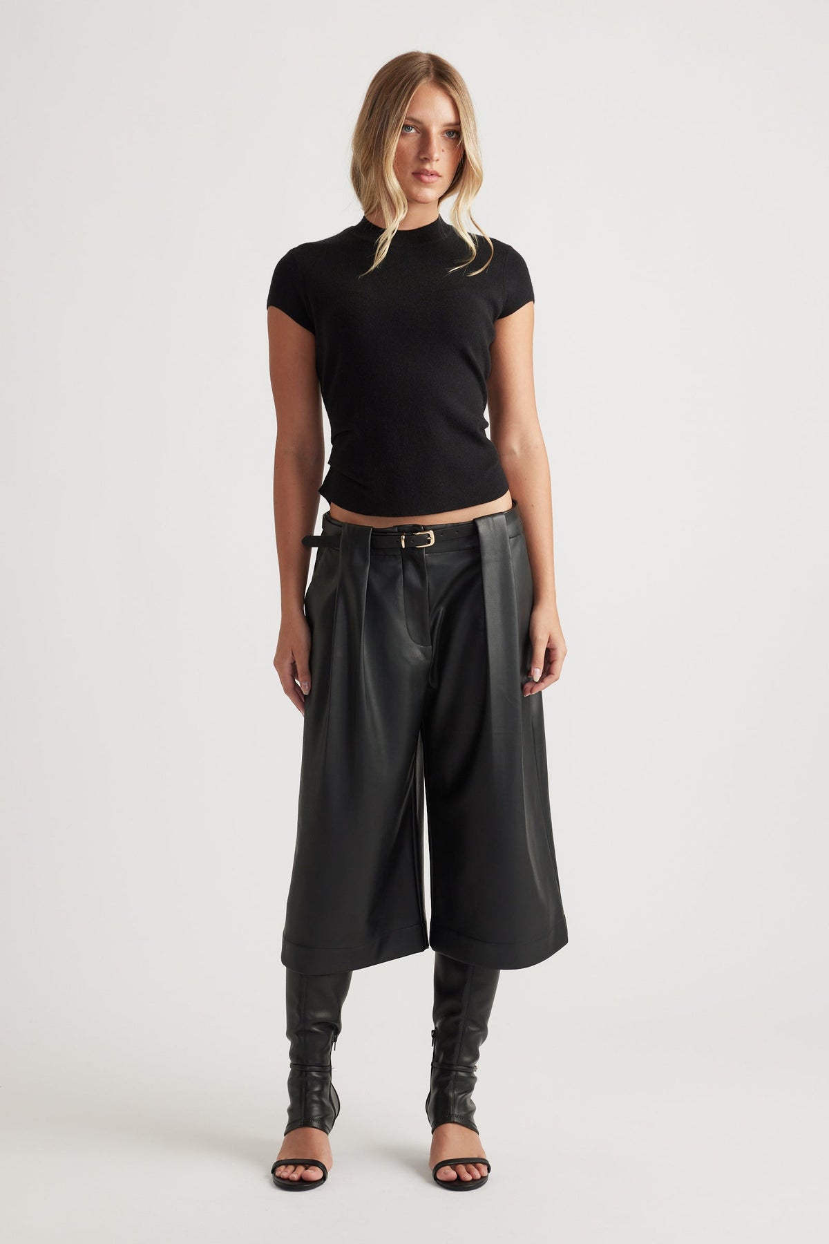 Woman wearing Lily Pleat Detail Knit Tee in black, styled with wide-leg cropped pants and heeled sandals by DECJUBA