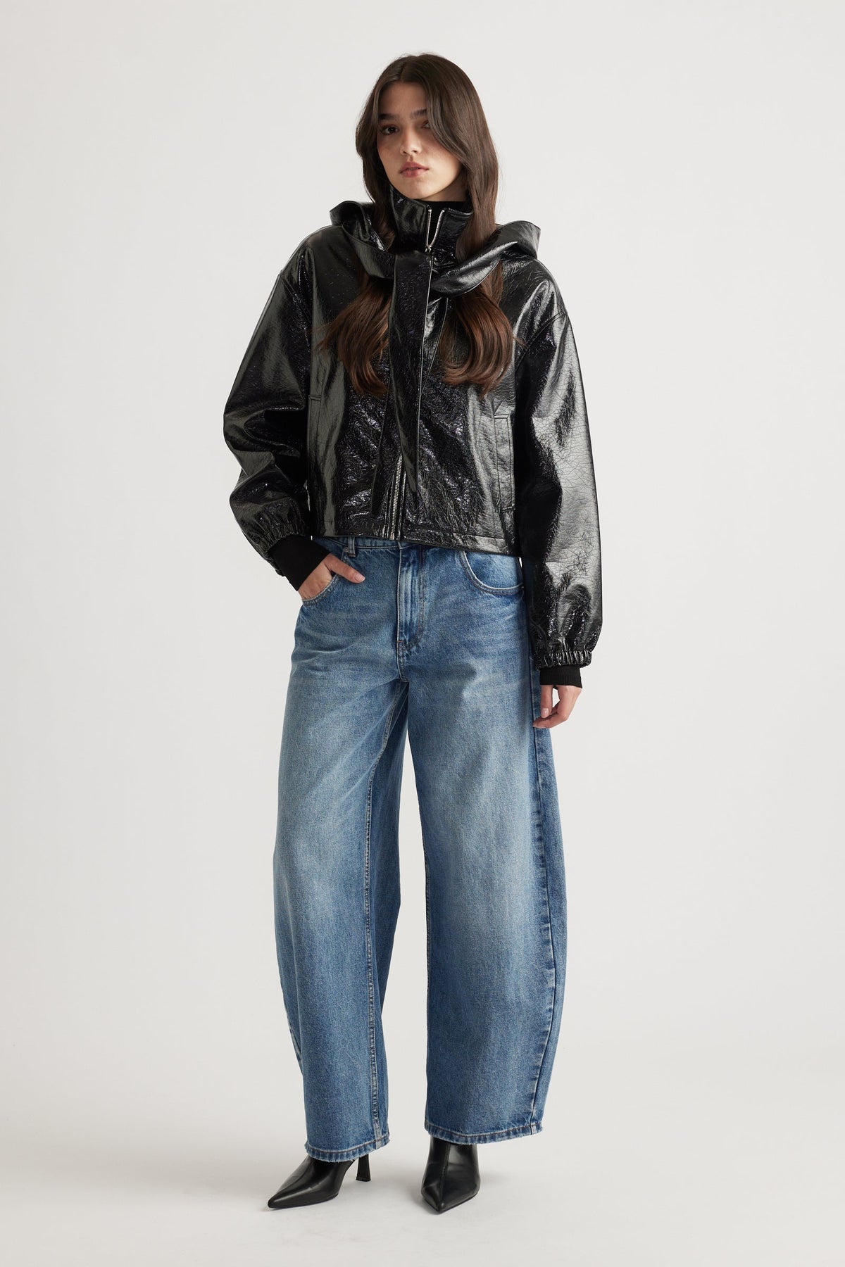 Model wearing a sleek black zip-up jacket styled with relaxed fit blue denim jeans and pointed black ankle boots