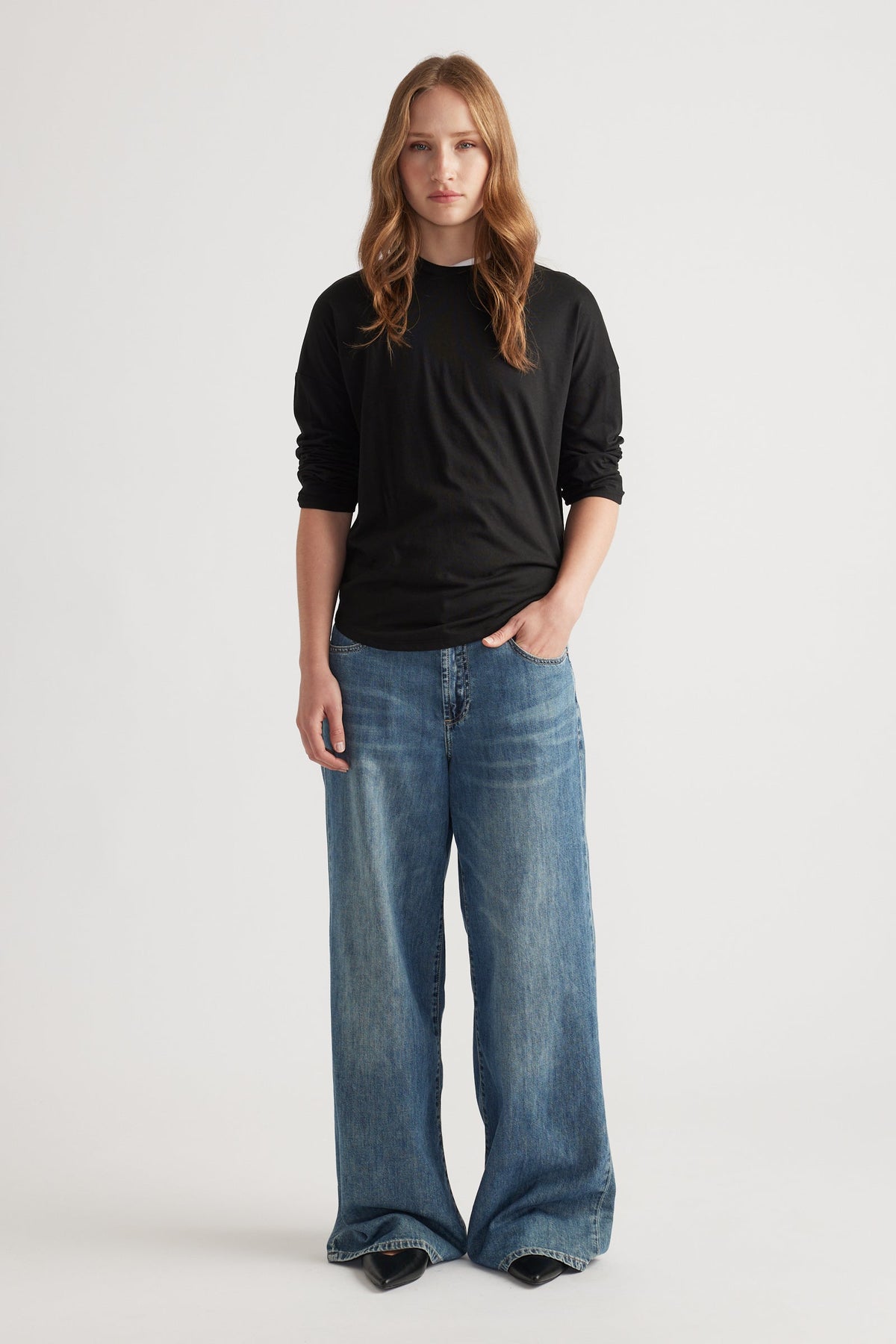 Woman wearing a fitted black long sleeve top styled with wide-leg faded blue denim jeans for a relaxed look