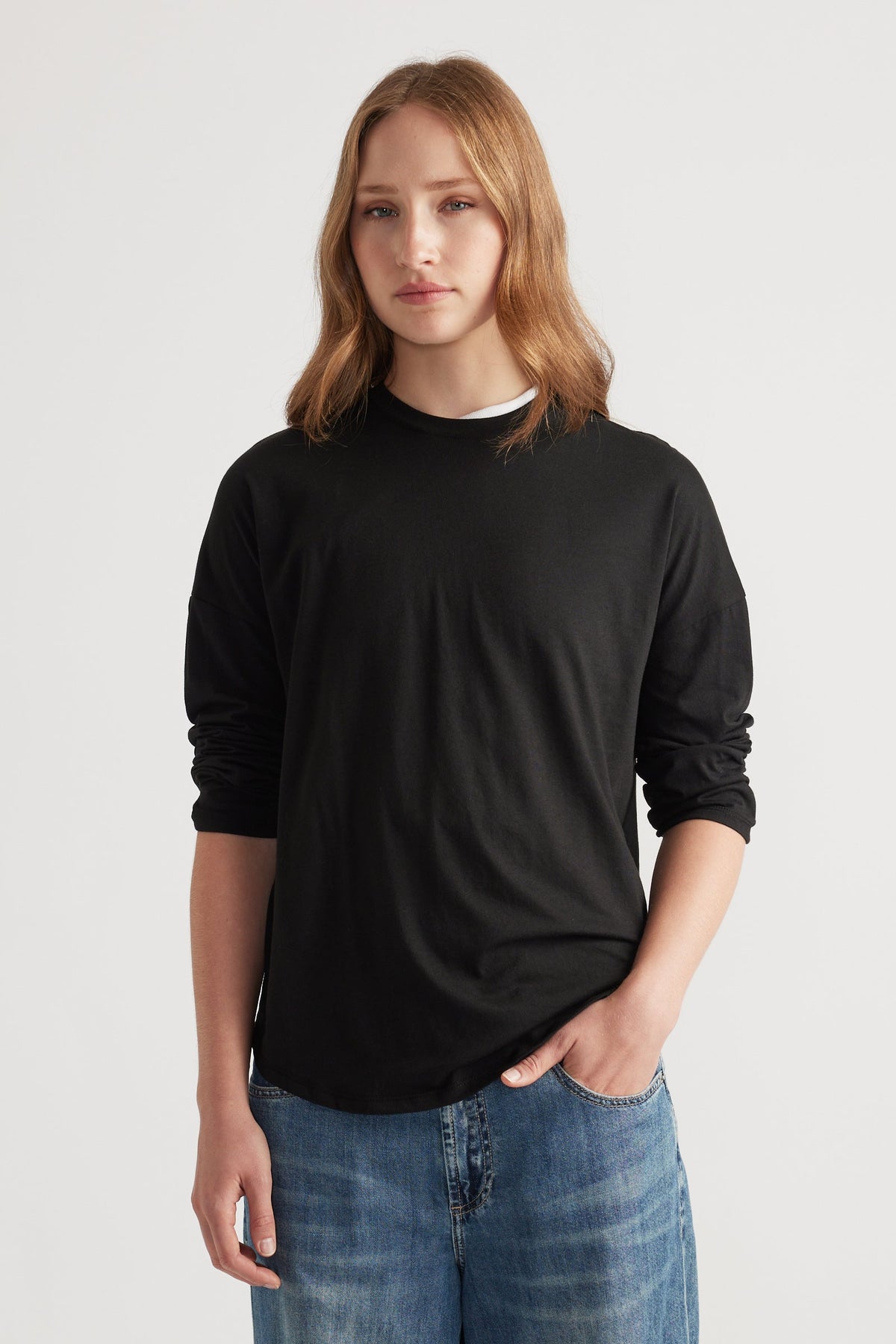Woman wearing a fitted black long sleeve top paired with relaxed blue denim jeans for a minimalist casual look