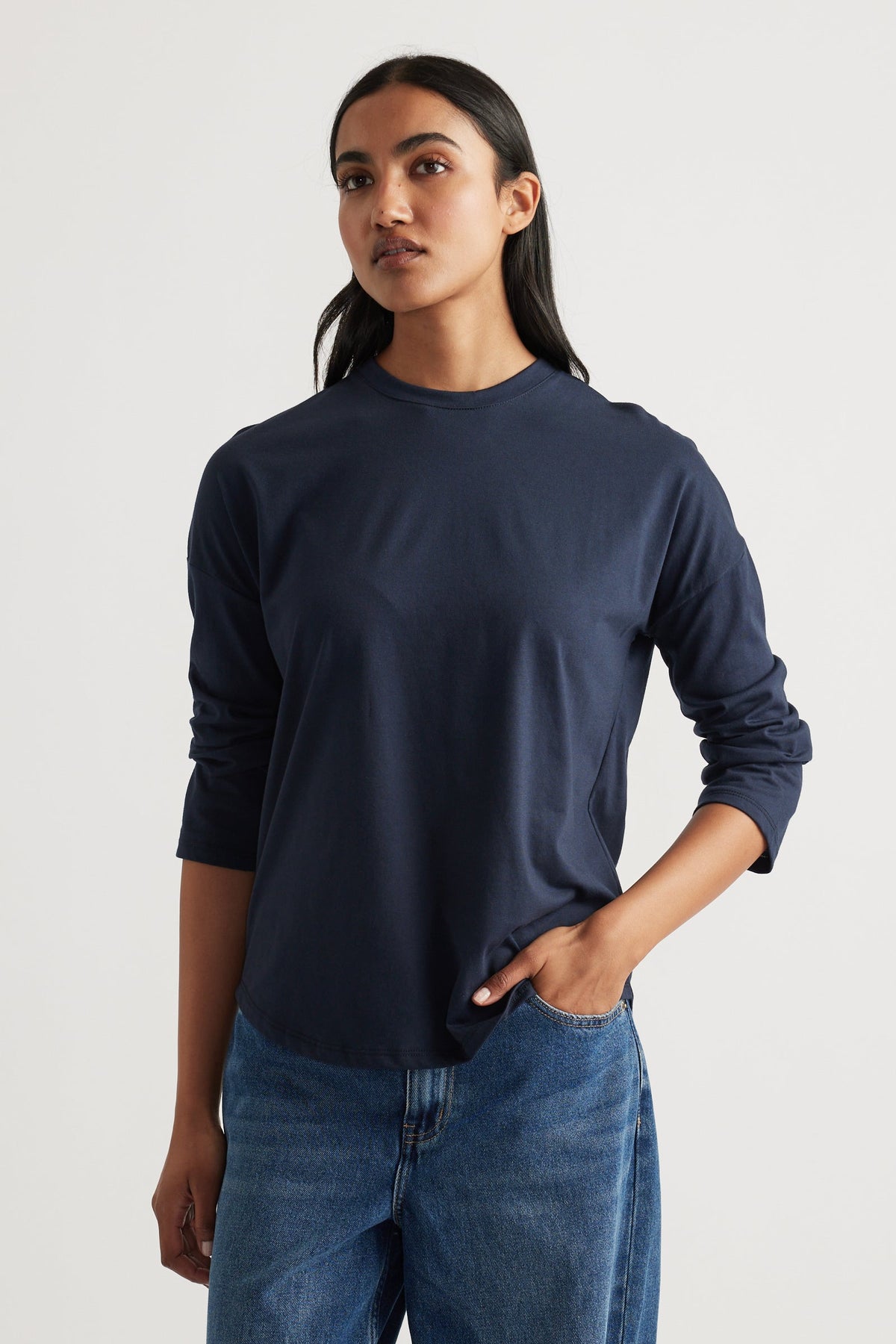 Woman wearing a classic navy long sleeve top paired with relaxed blue denim jeans for a timeless casual outfit