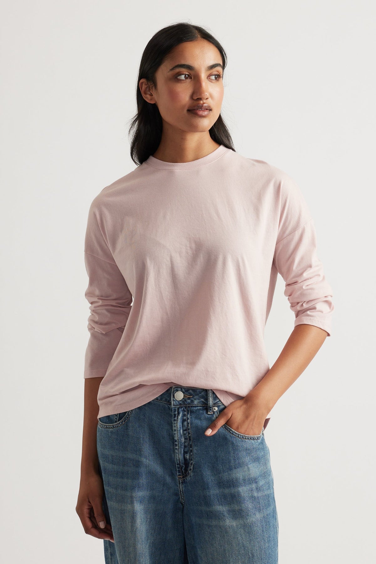 Woman wearing a soft pink long sleeve top paired with relaxed blue denim jeans for a casual, effortless look