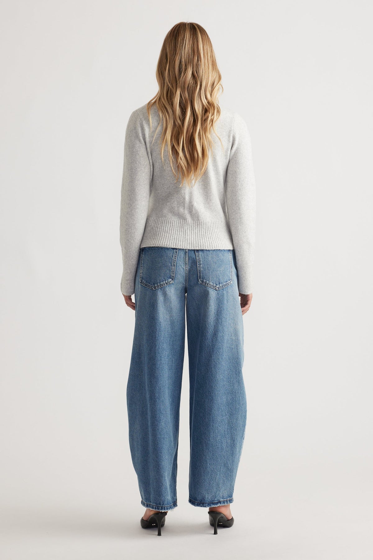 Back view of woman wearing Tamica Layered Jumper in soft grey paired with relaxed wide-leg blue jeans and black heels
