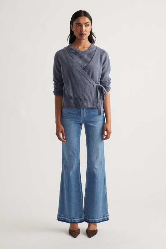 Woman wearing Tamica Layered Jumper in soft shadow blue layered over knit top, styled with flared denim jeans and pointed shoes