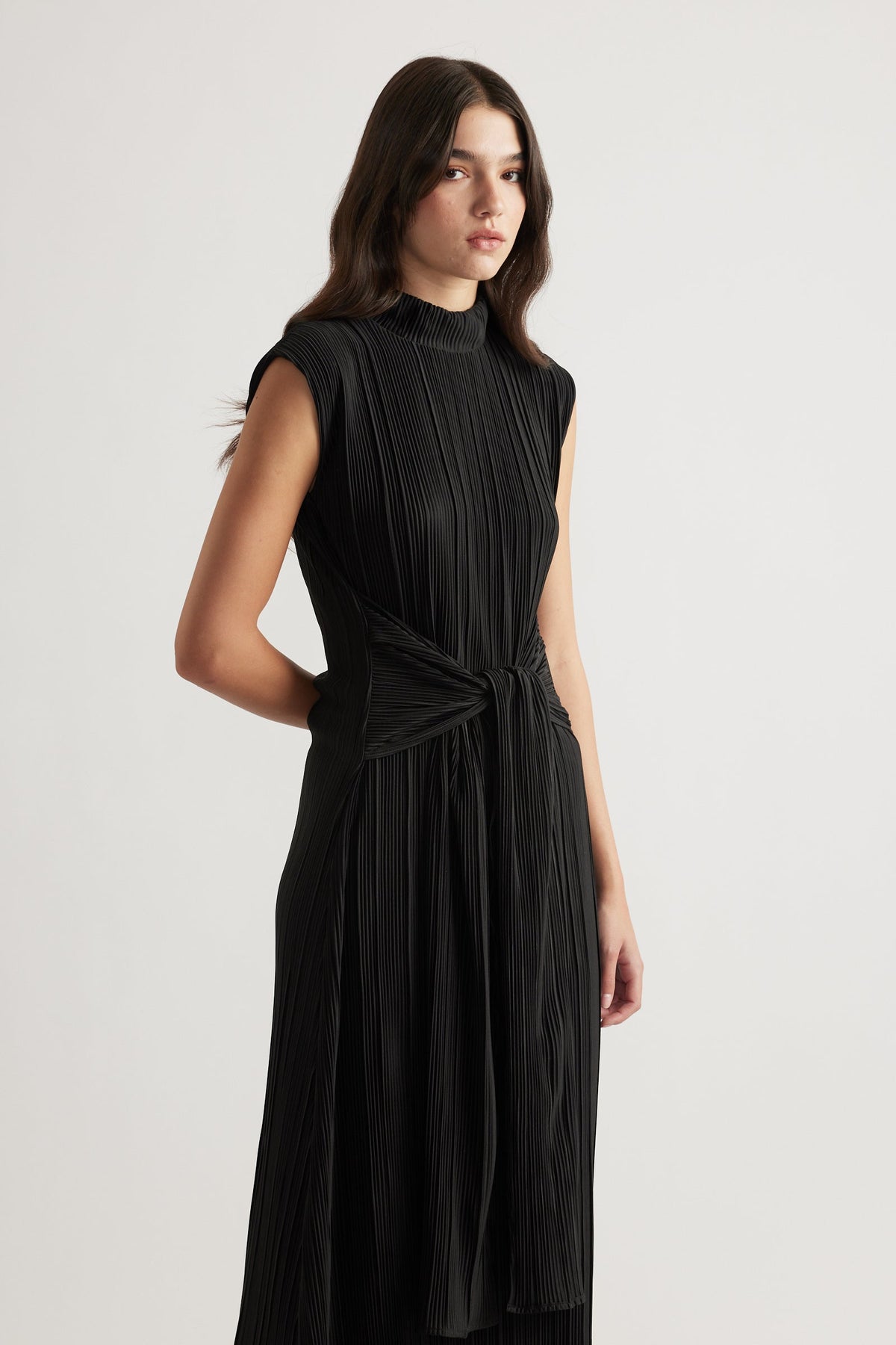Sleeveless black pleated maxi dress with a high neck and tie waist detail for elegant everyday wear