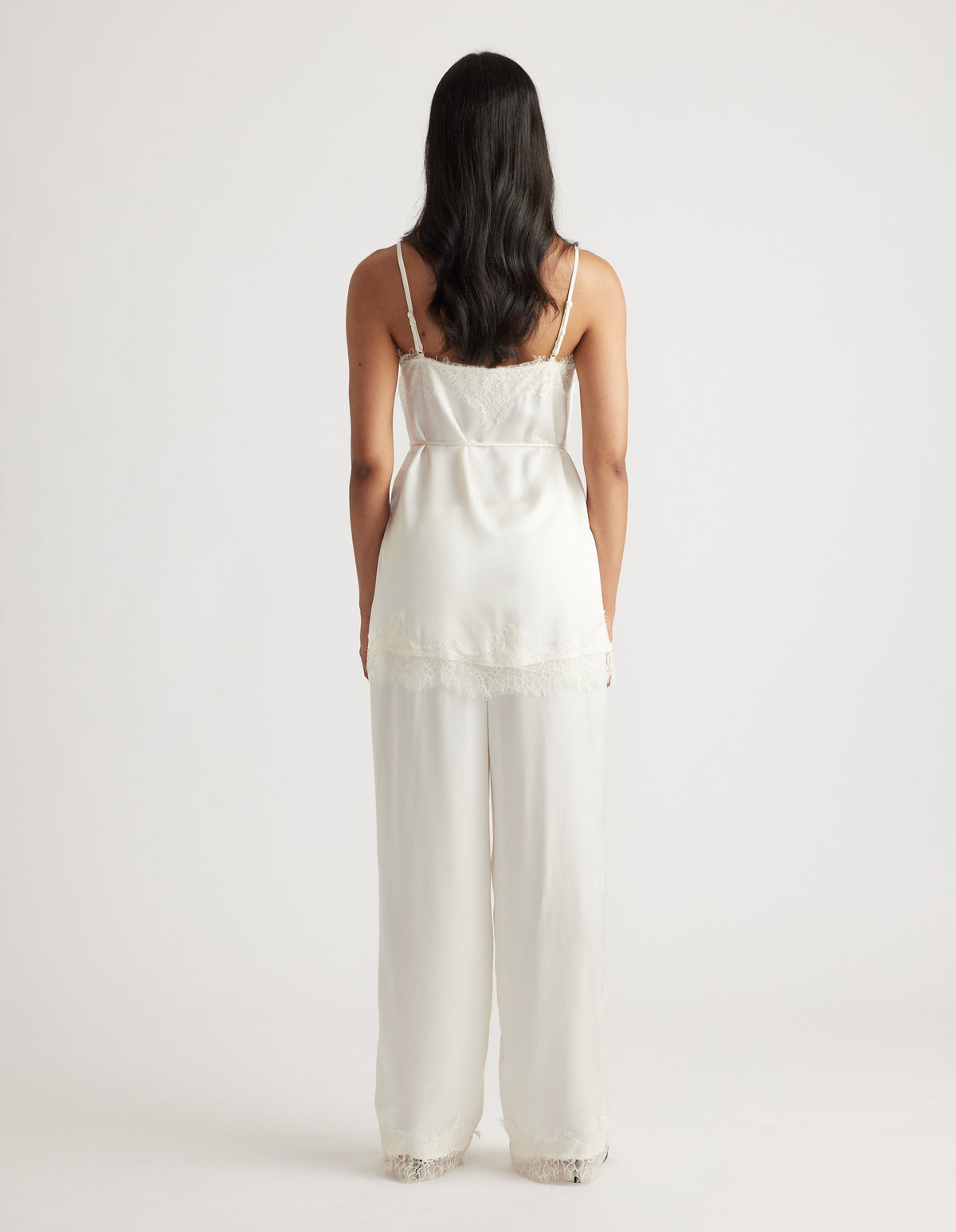 Back view of a white lace-trimmed camisole top paired with matching wide-leg pants in a relaxed fit.