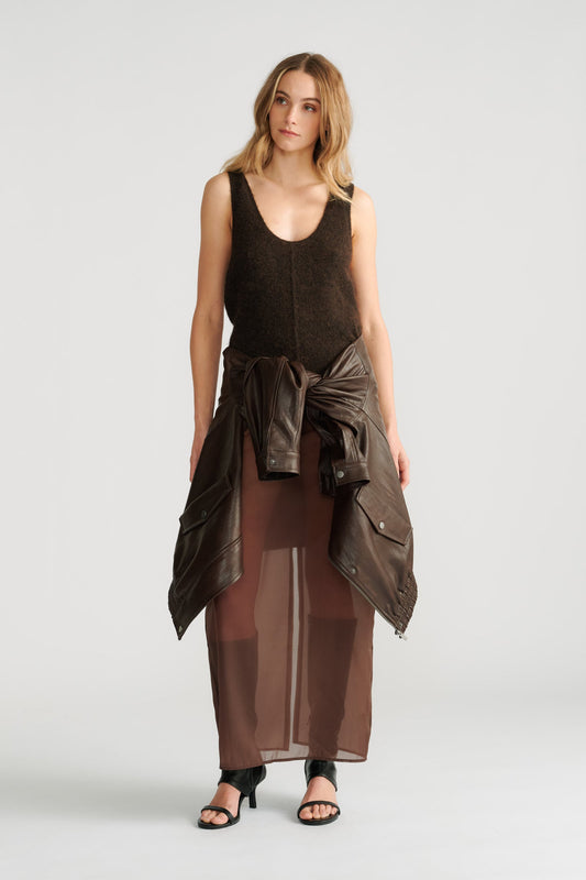 Woman wearing a dark brown fluffy knit tank with a tied leather jacket and sheer brown maxi skirt paired with black heels