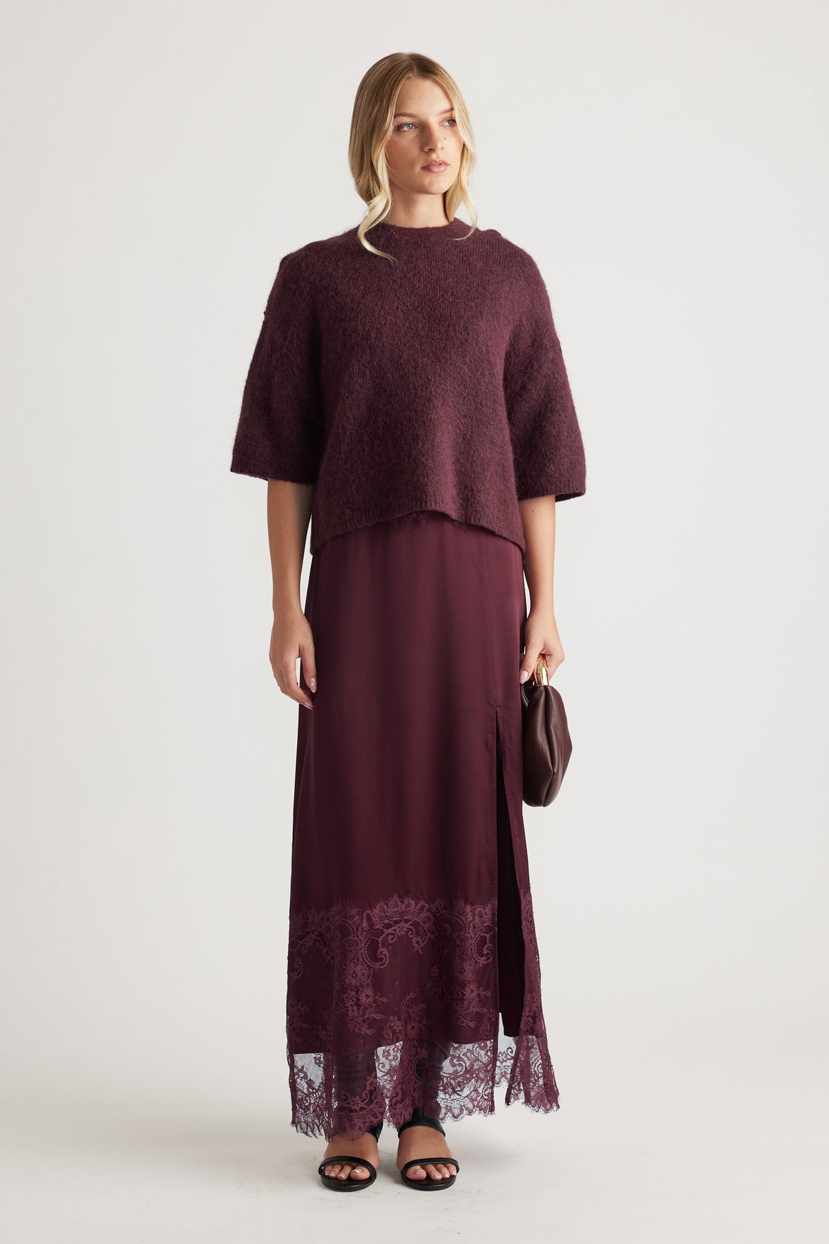 Woman wearing a textured burgundy knit top paired with a matching lace-trimmed maxi skirt and black sandals