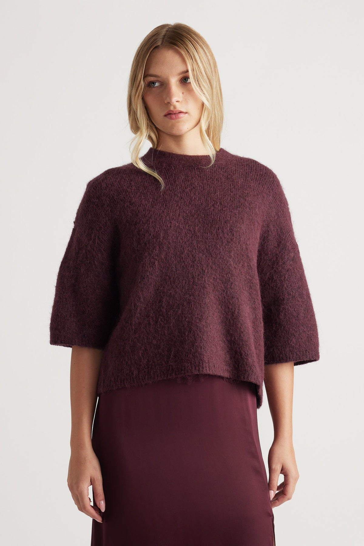Woman wearing a burgundy fluffy knit tee with elbow-length sleeves paired with a matching sleek skirt for a cozy look
