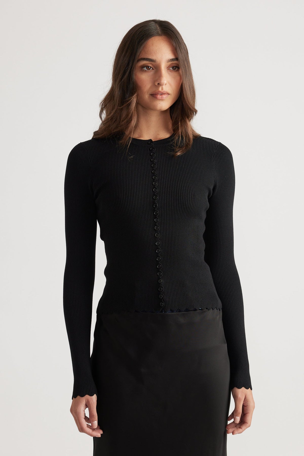 Close-fitting black ribbed top with scalloped edges and a row of delicate buttons down the front.