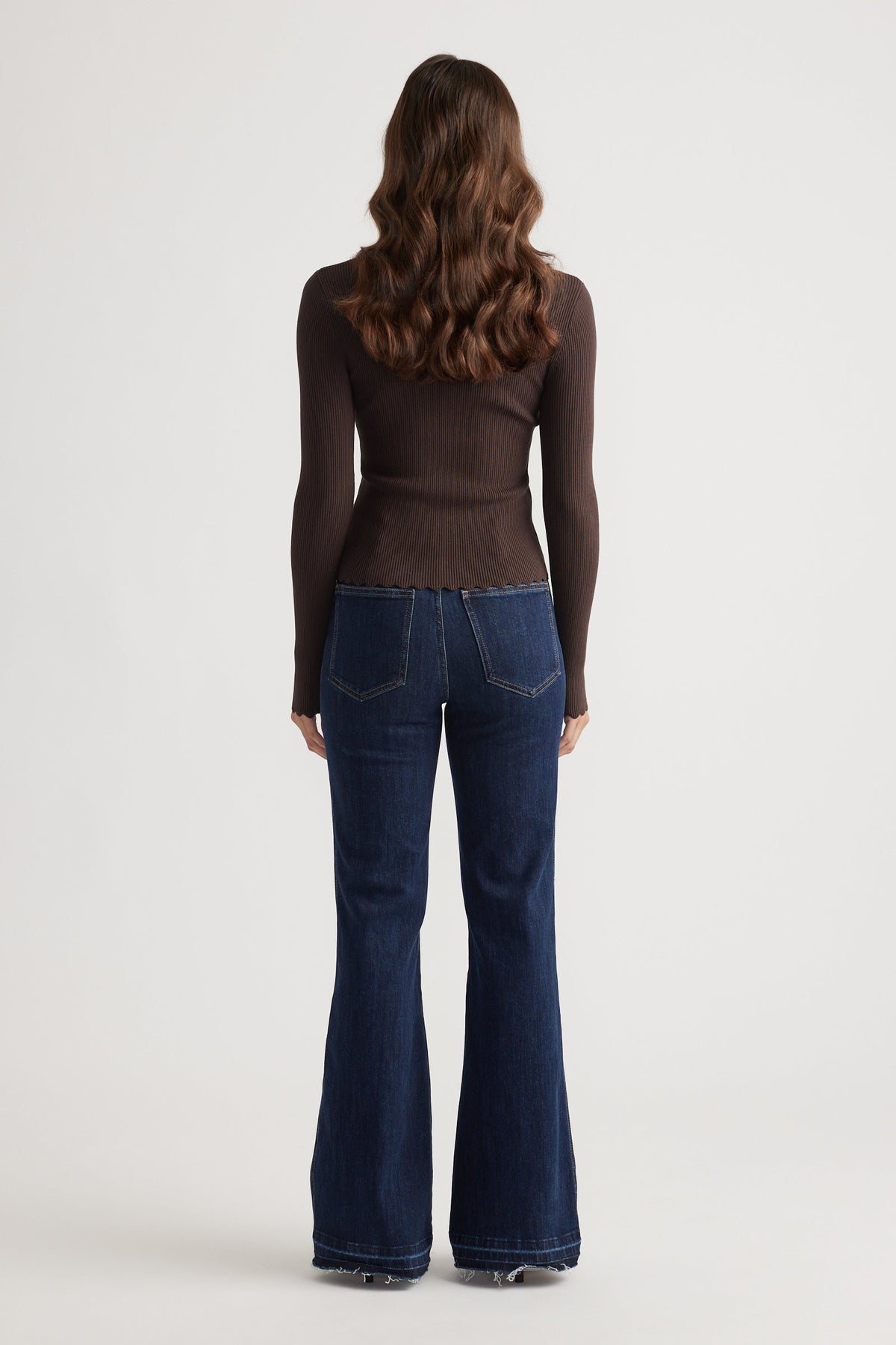 Back view of slim-fit dark brown top paired with high-waisted dark blue flared denim jeans for a sleek casual look