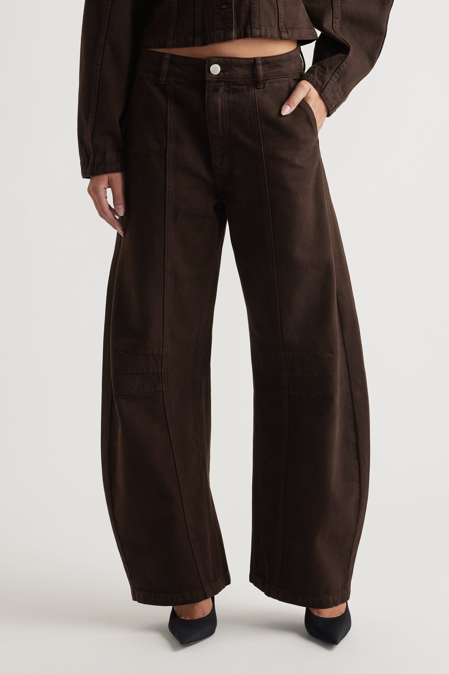 Person wearing brown high-waisted jeans on a white background