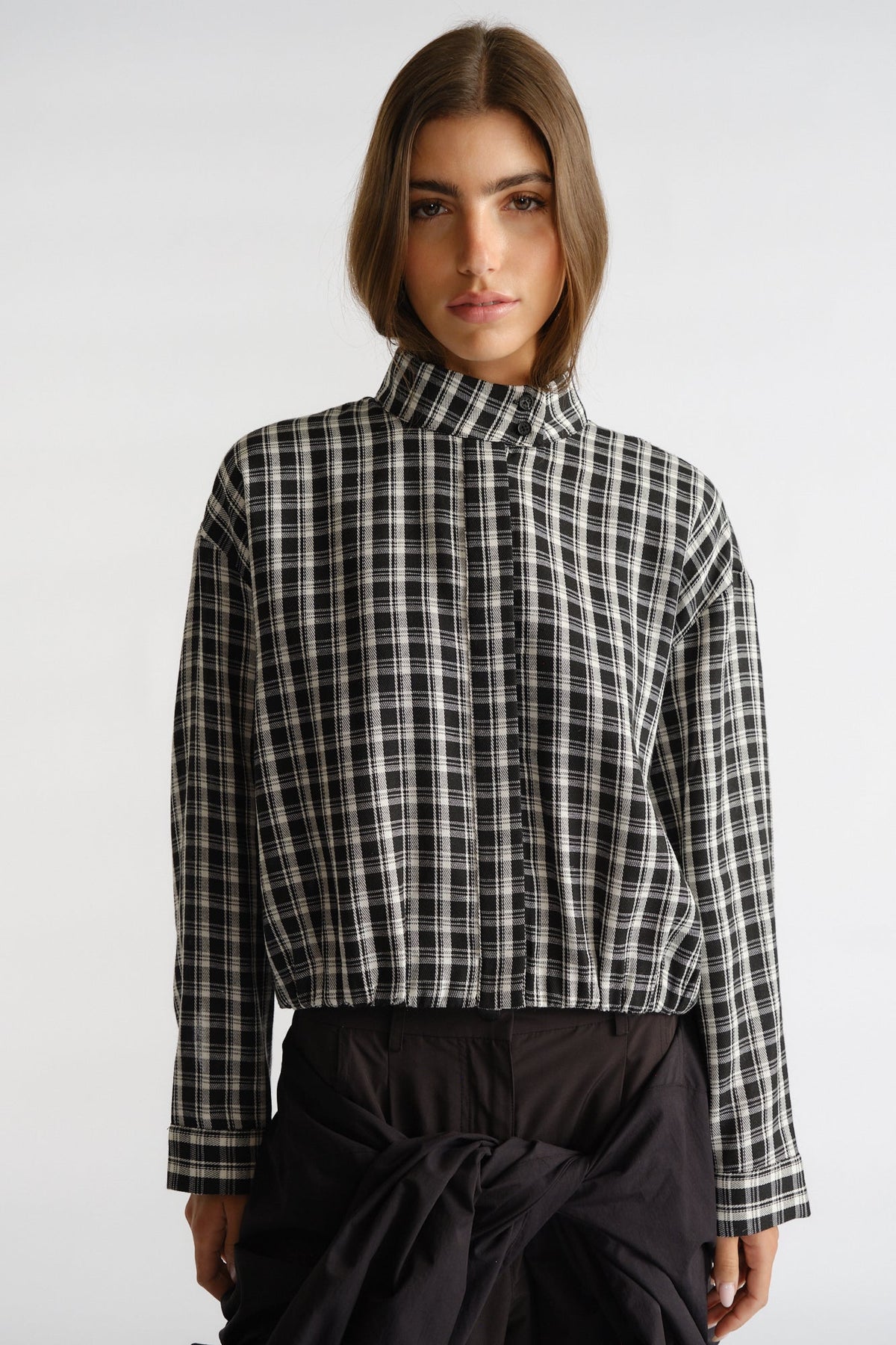 Woman wearing a relaxed-fit black and ivory check shirt with a stand collar and long sleeves for a chic casual look