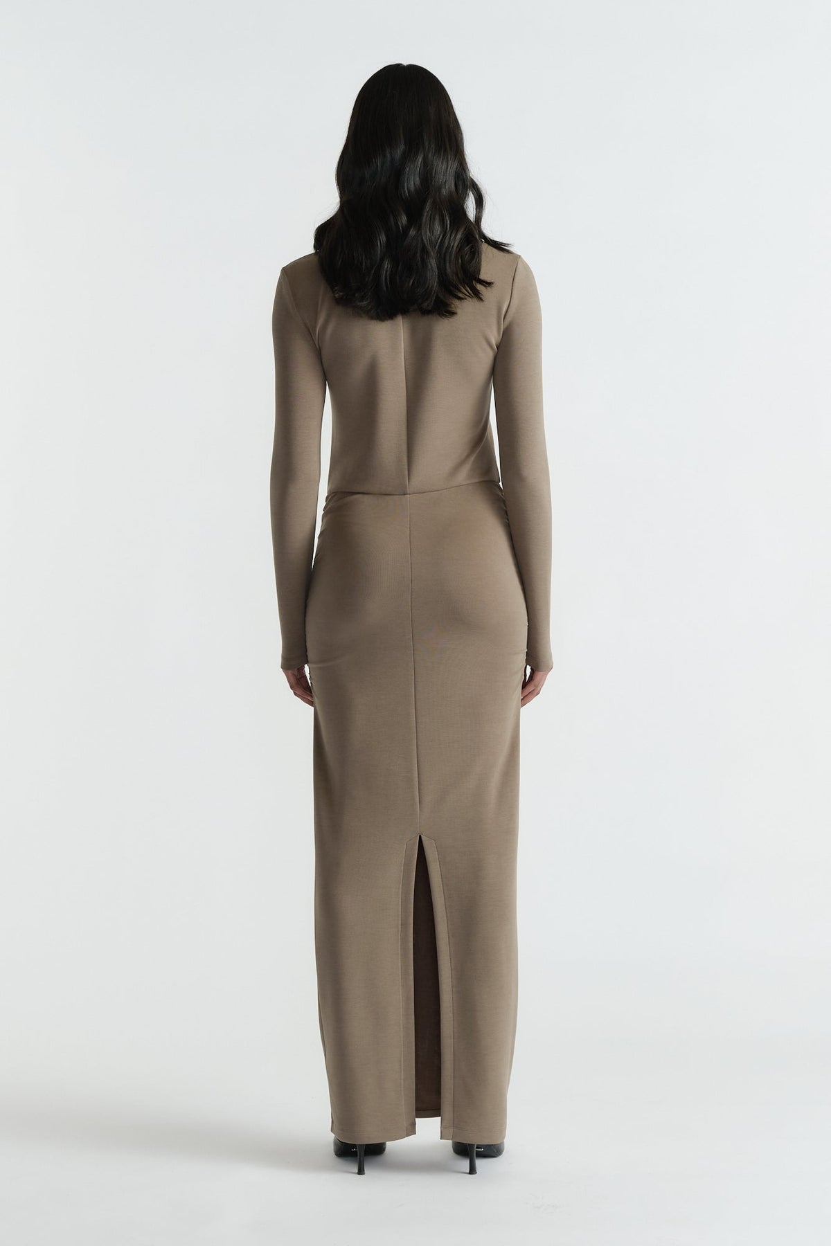 Back view of woman wearing a fitted khaki long-sleeve midi dress with a back slit and clean seam details