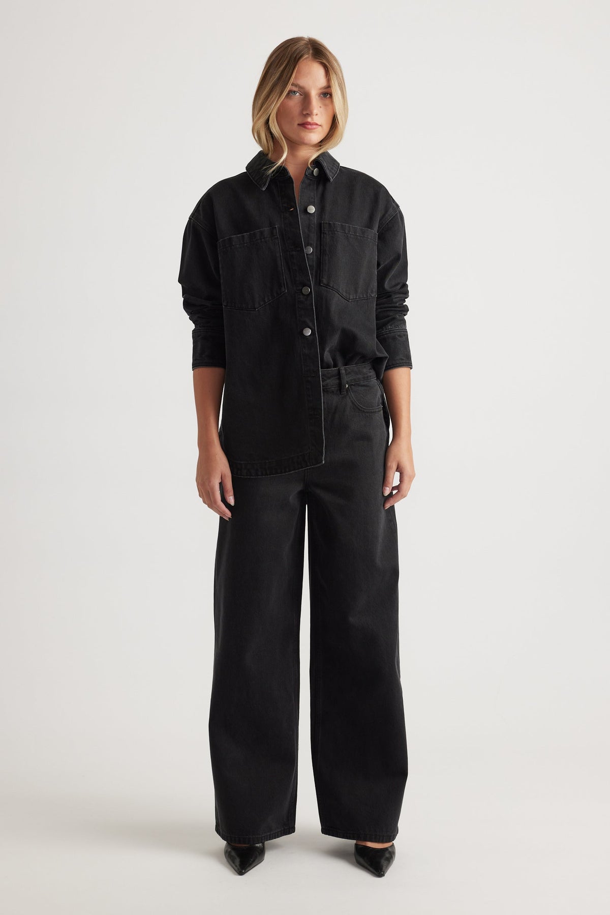 Woman wearing Elena Wide Leg Jean in black denim paired with a matching black denim shirt and pointed shoes by DECJUBA