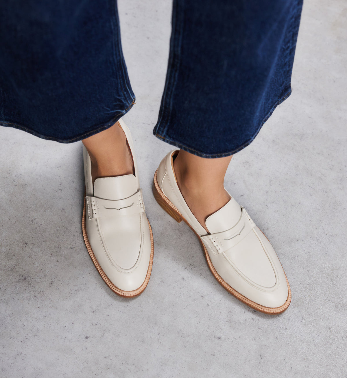 pair of beige loafers on foot with denim jeans