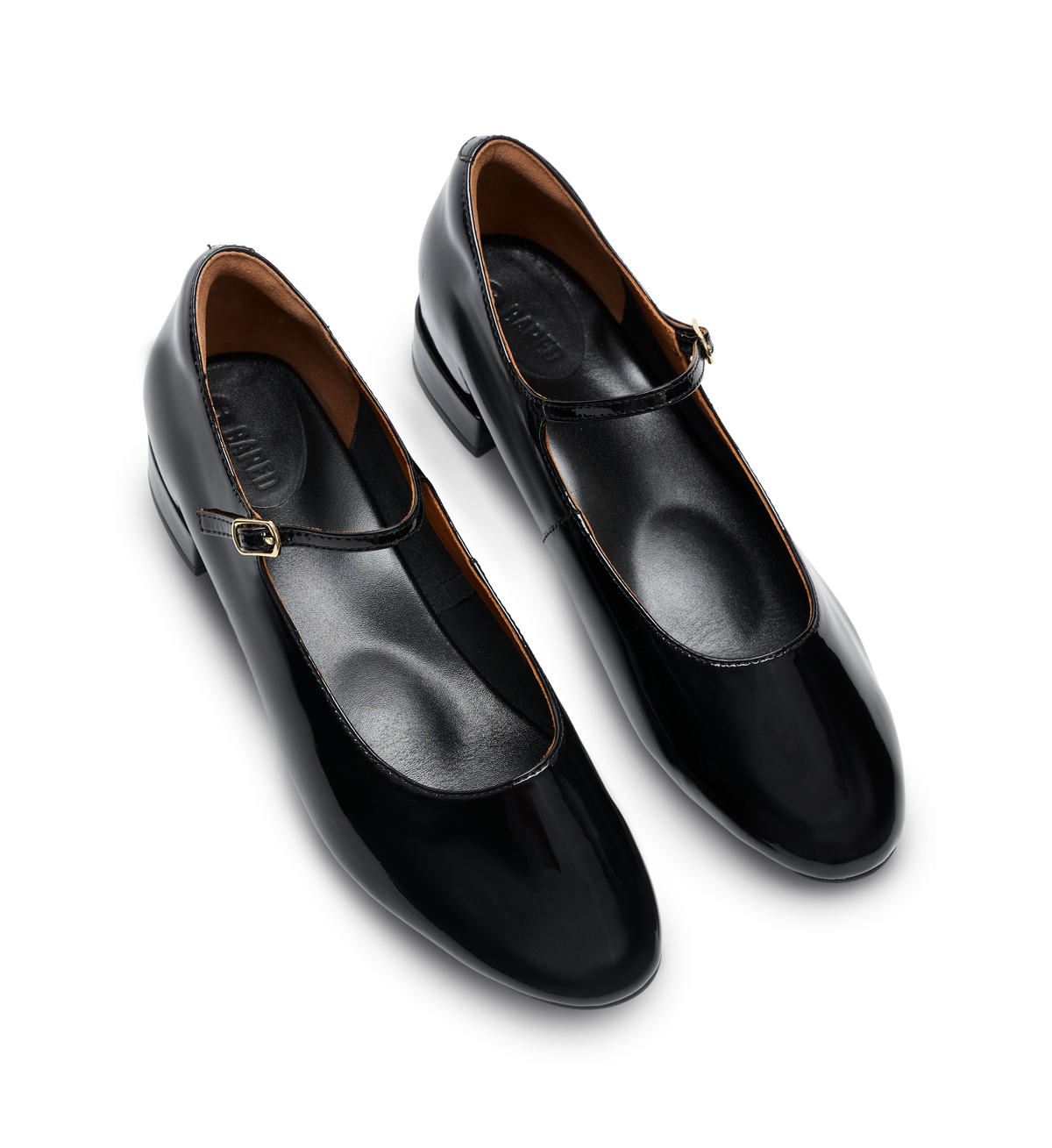 Pair of black leather ballet flats with a strap on a white background