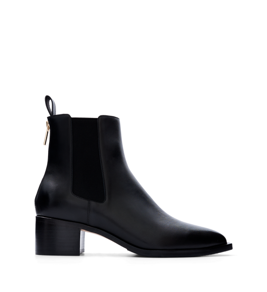 A black leather heeled boot with elastic side panels and a pointed toe. It features a pull tab and a back zip for easy slip-on wear.