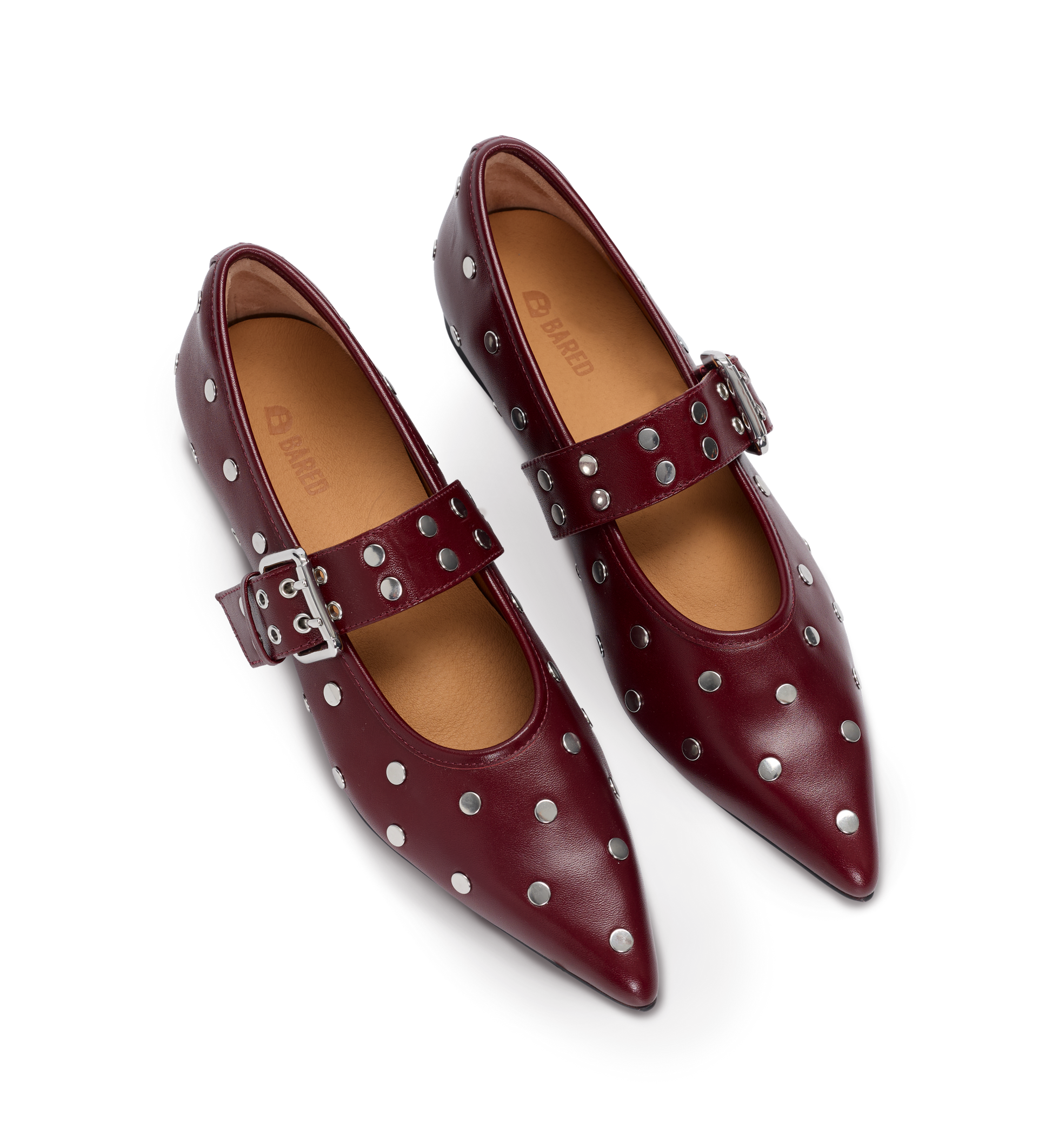 Pair of red ballet flats with silver studs and buckles on a white background