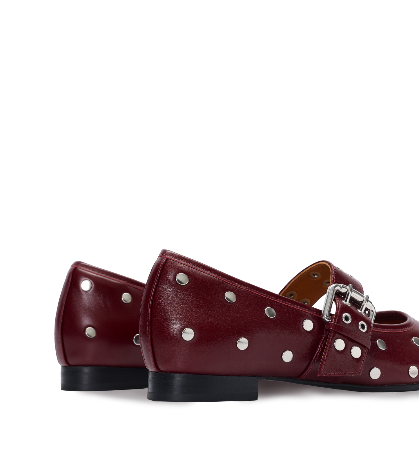 Pair of red ballet flats with silver studs and a buckle on a white background