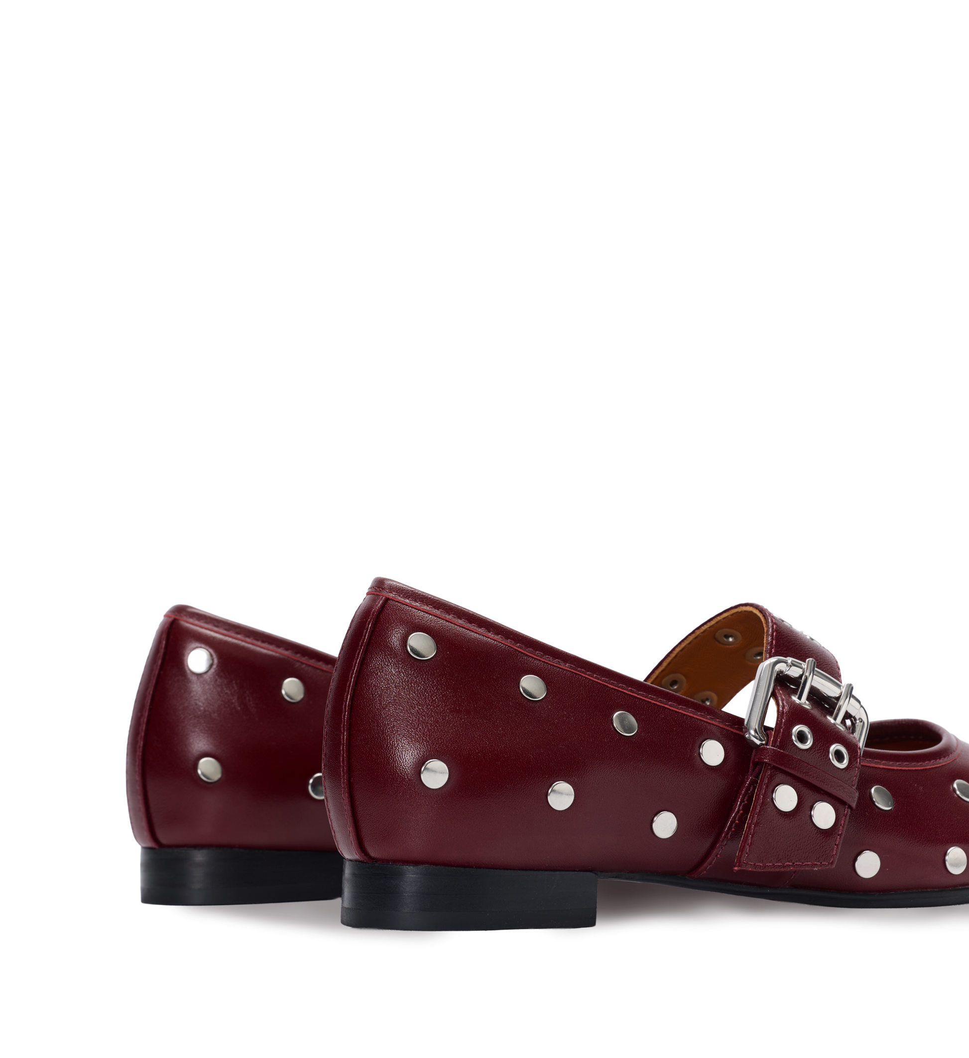Pair of red ballet flats with silver studs and a buckle on a white background