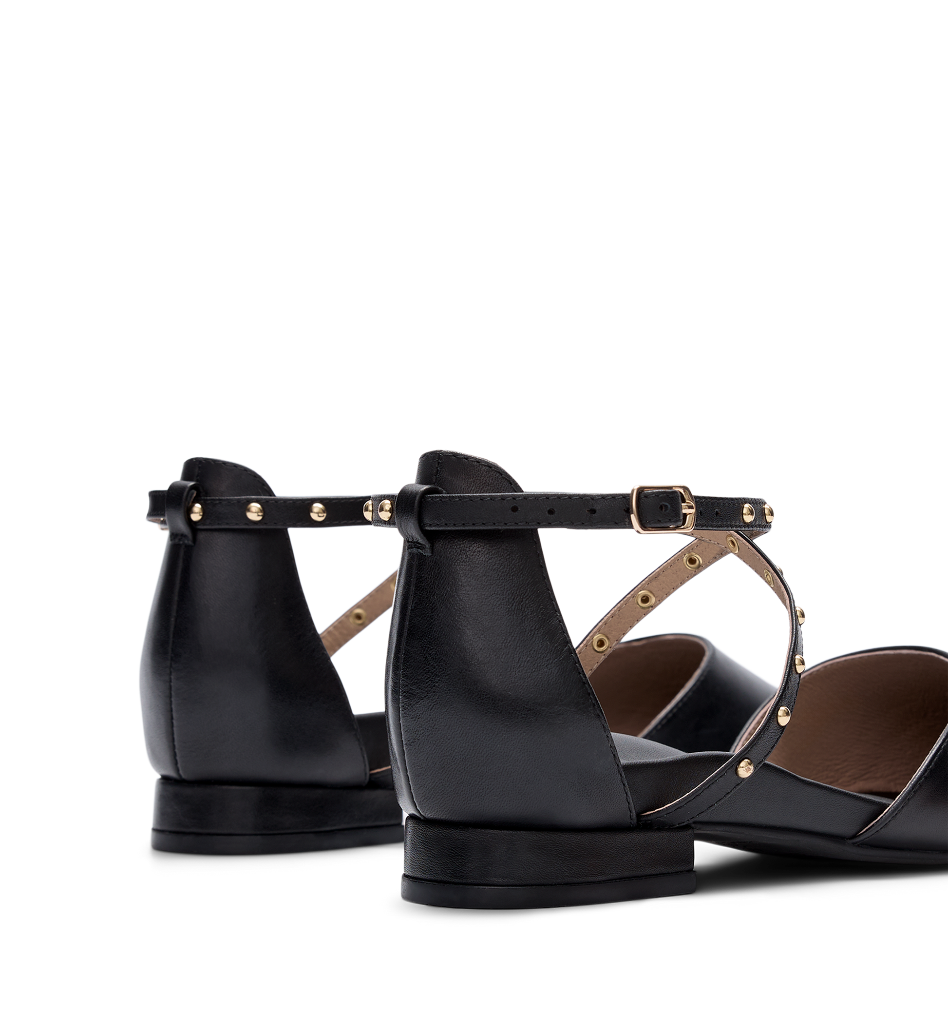 Black leather flats with gold accents on a white background