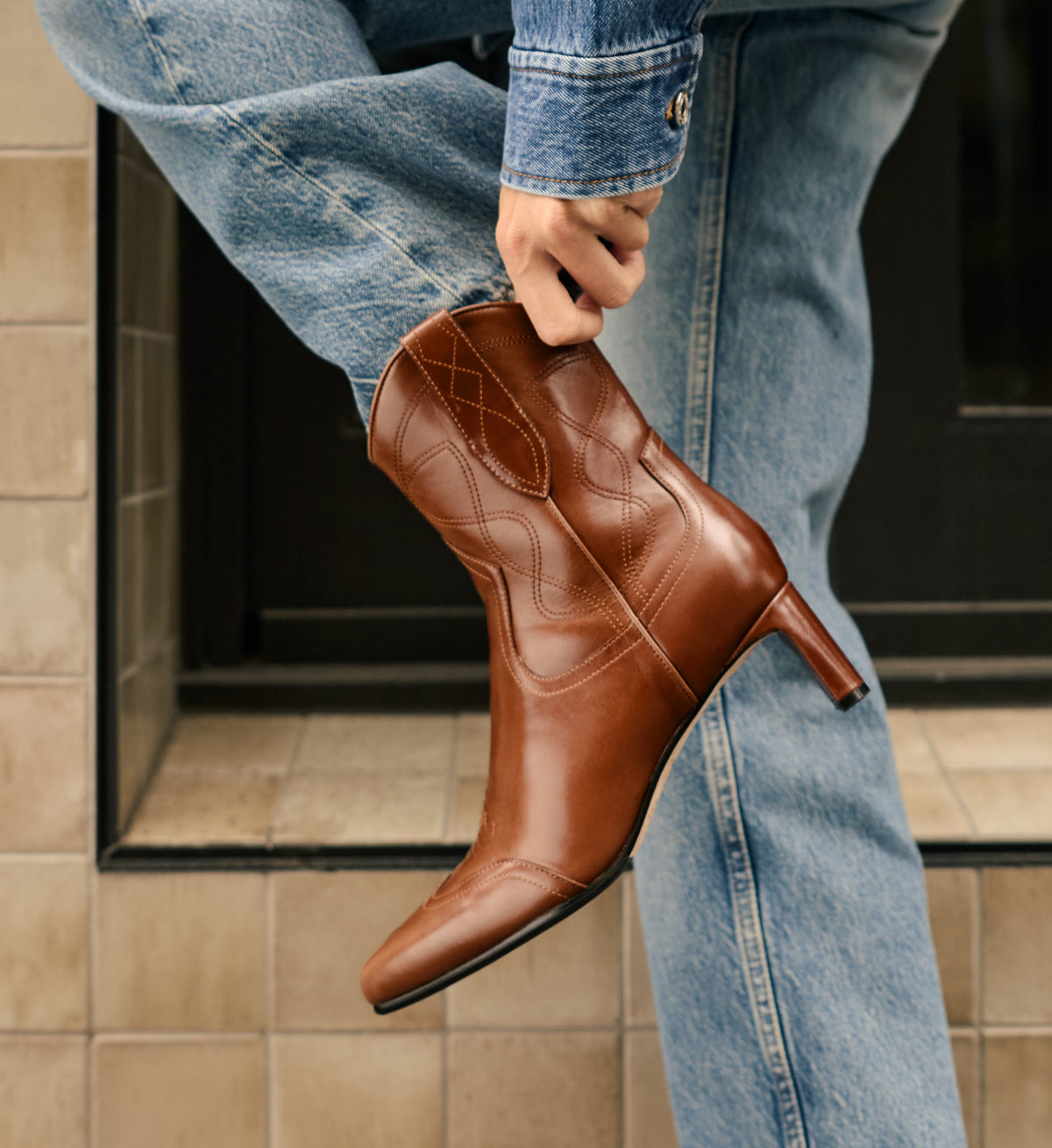 Brown leather boot being worn with blue jeans.