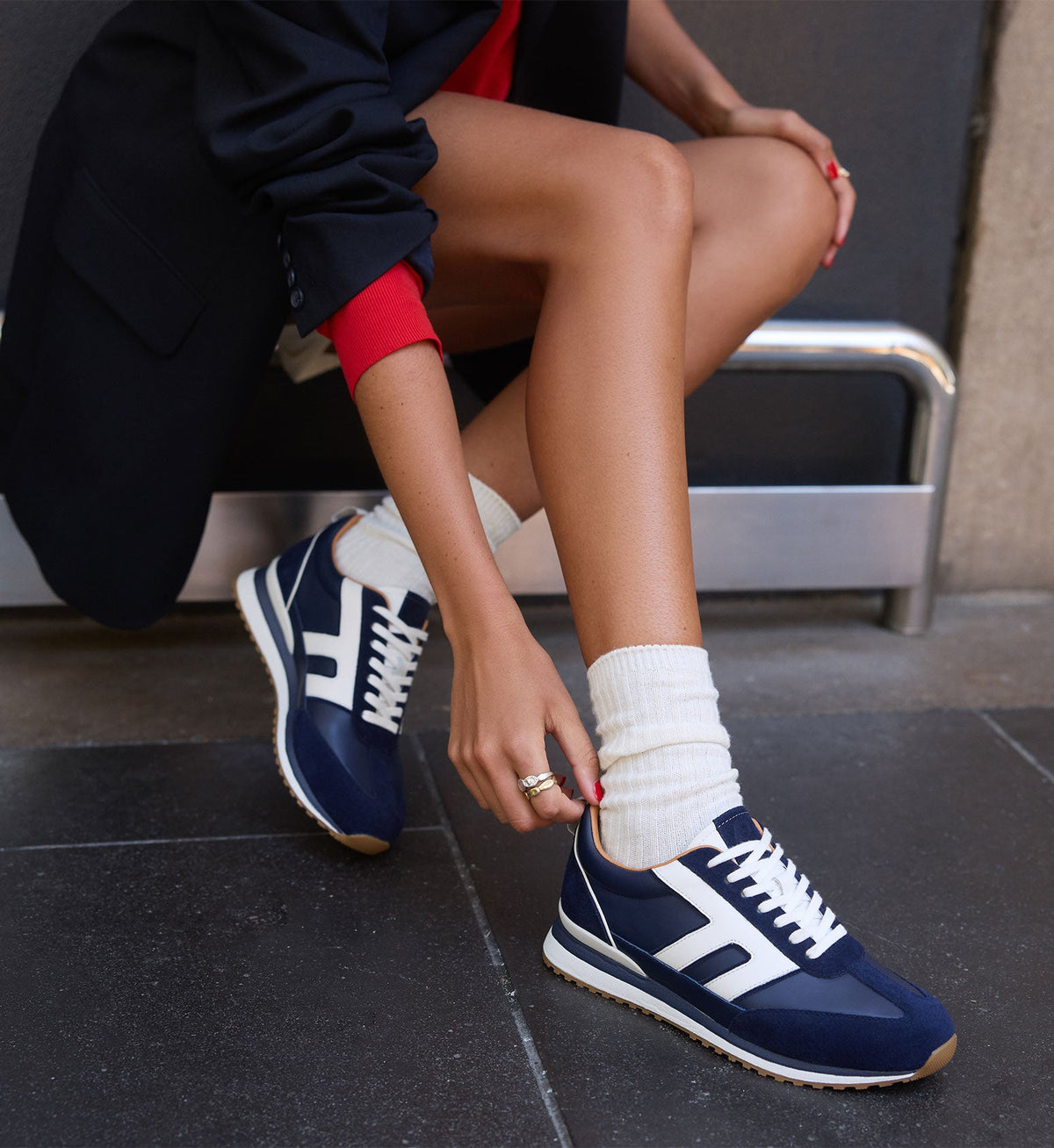 model wearing navy sneakers with white socks and a red top with a black blazer