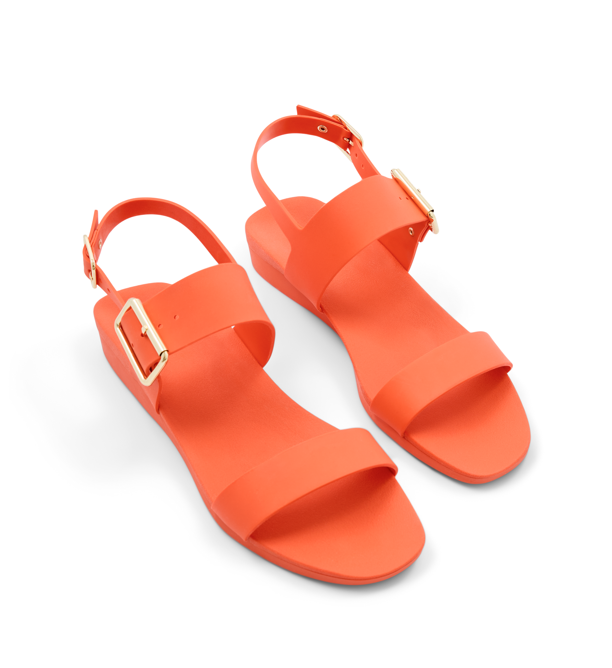 Pair of orange sandals with gold buckles on a white background