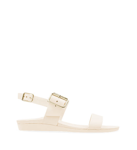 A flat sandal with white straps and a gold buckle, featuring a contoured footbed.